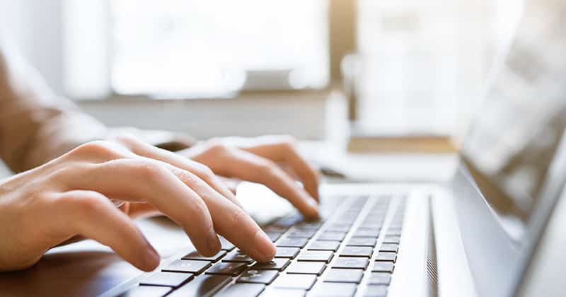 person typing their email marketing on a laptop keyboard