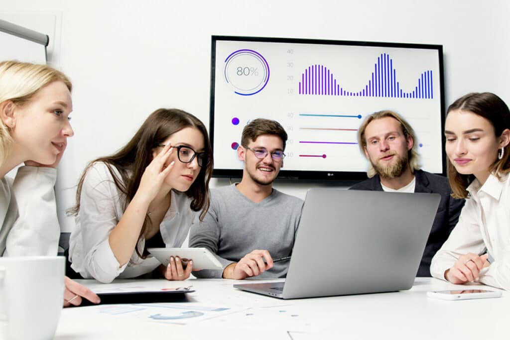 Team reviewing project data on a laptop while using construction project management software together.