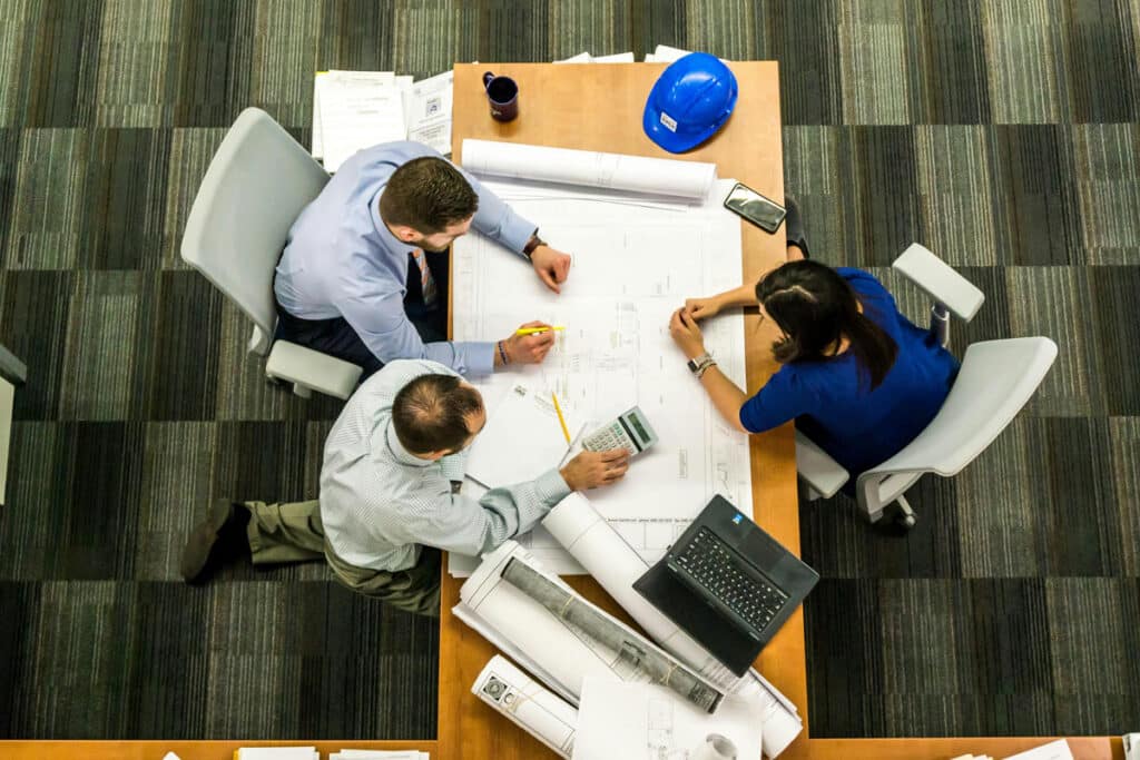 Team reviewing blueprints and project plans while using a construction project management software.