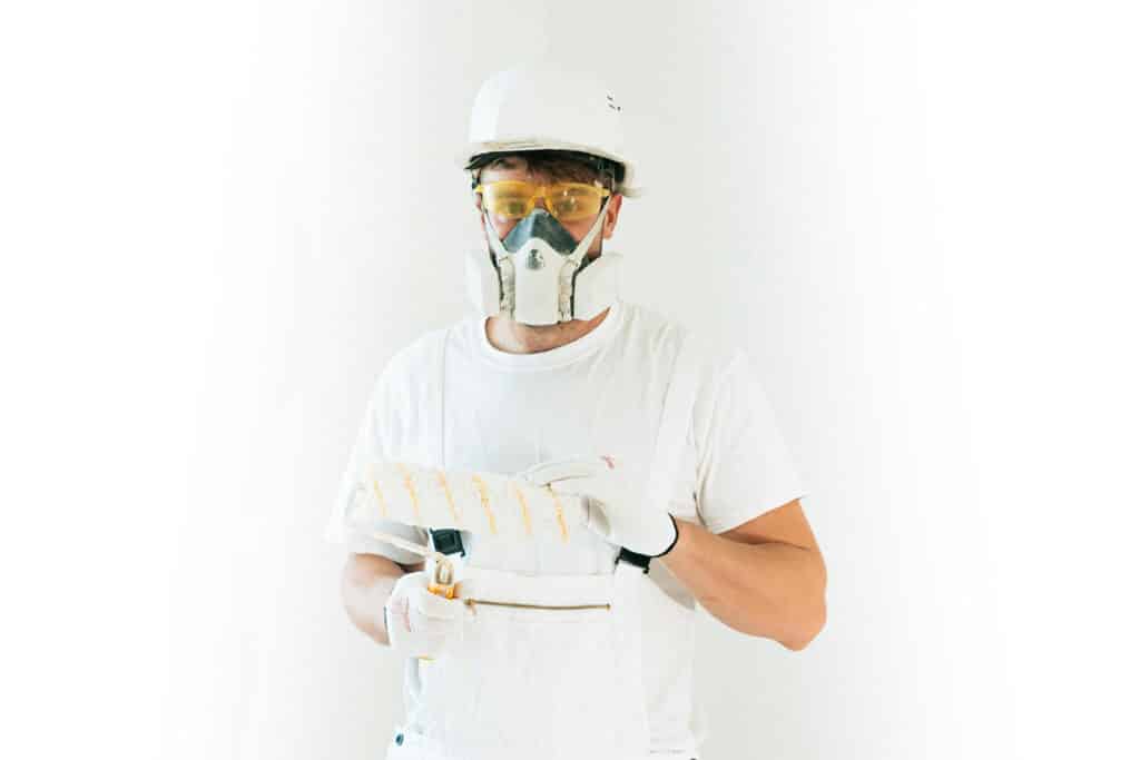 Painter wearing safety gear holding a roller, showing labor needs in home services industry trends in 2025.