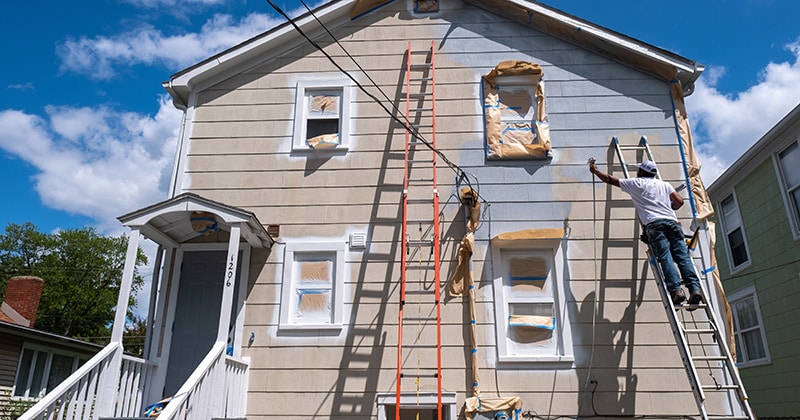a person painting the exterior of a house
