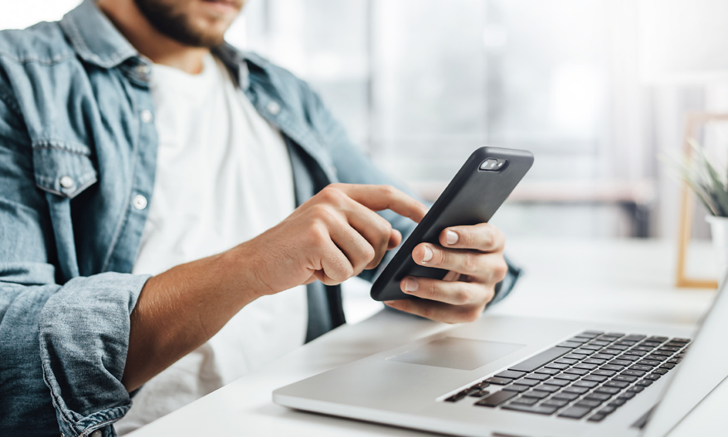 man using mobile device and laptop