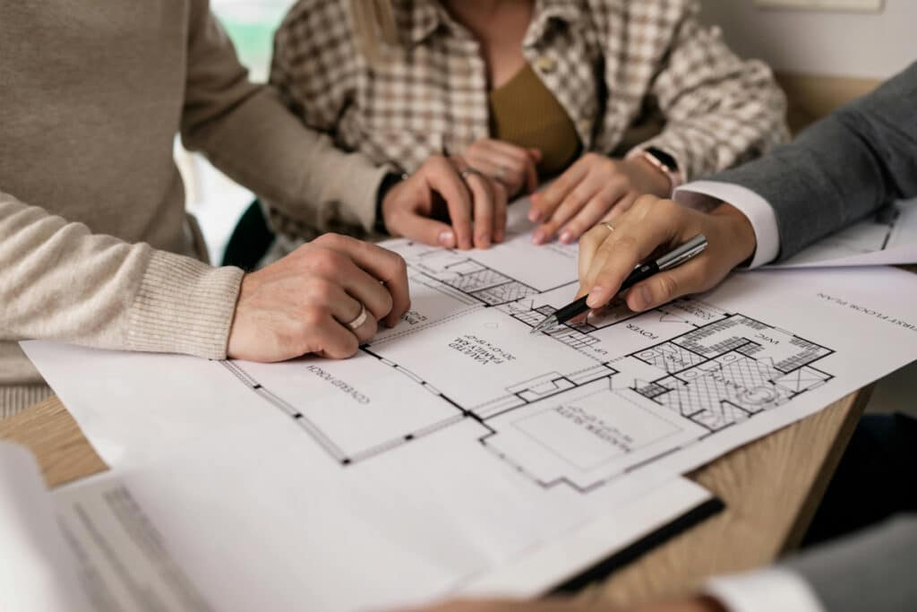 People reviewing a floor plan together, illustrating the work of a licensed general contractor.
