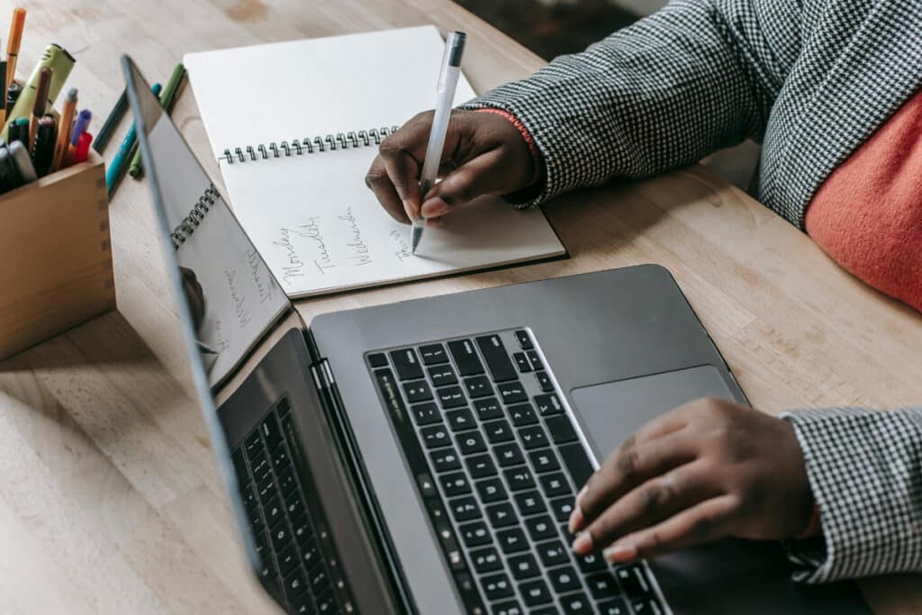Person writing in a notebook beside a laptop, showing online scheduling in home services industry trends in 2025.