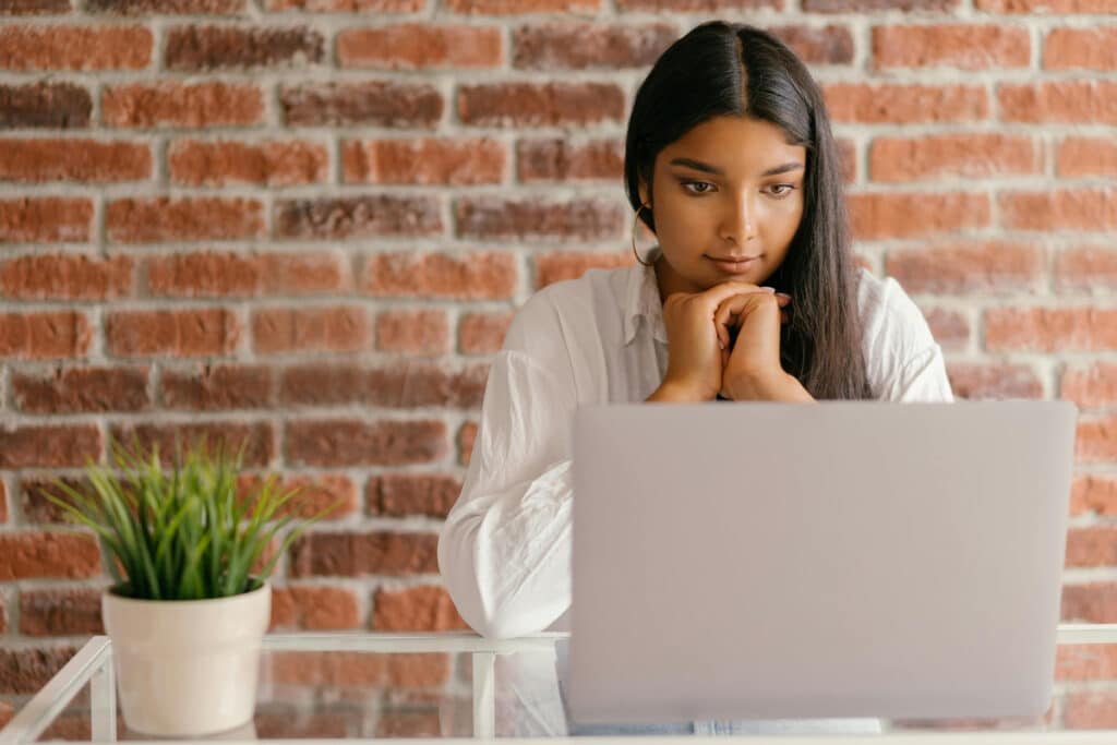Person working on a laptop at a glass desk, representing contractor estimating software use.