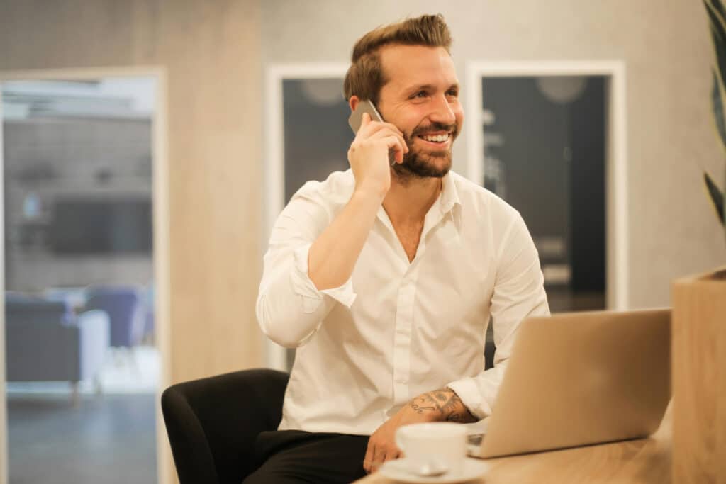Expert with a home improvement license taking a call while working on a laptop in an office.