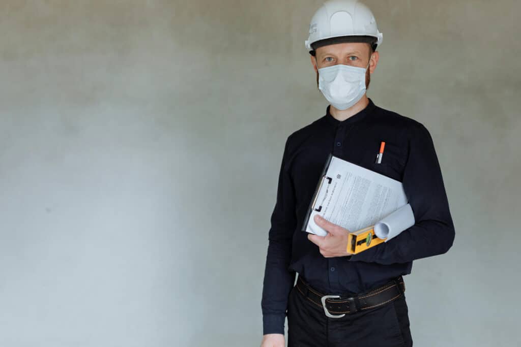 Expert with a home improvement license holding documents and tools inside a renovation site.