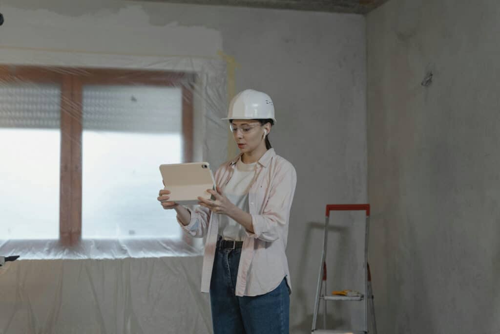 Expert with a home improvement license using a tablet inside a renovation site.
